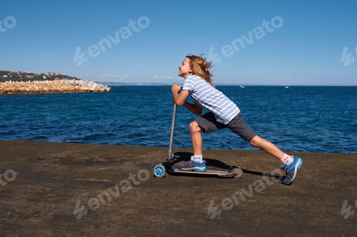 Preview: Boy riding a scooter on a pier at sunny day
