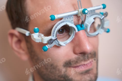 Preview: Man is examining his visual acuity with special lenses in ophthalmology center