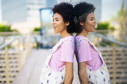 Preview: Positive black woman near building on street