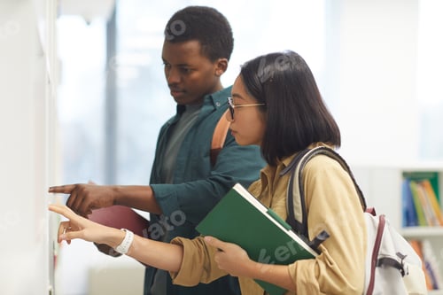 Preview: Two Students Choosing Books in Library
