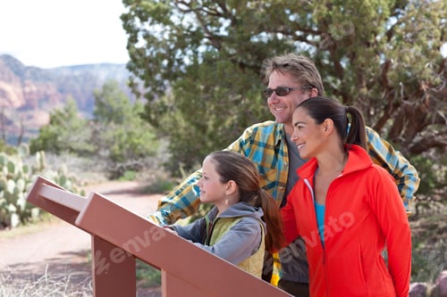 Preview: Mature parents and daughter reading sign whilst hiking, Sedona, Arizona, USA