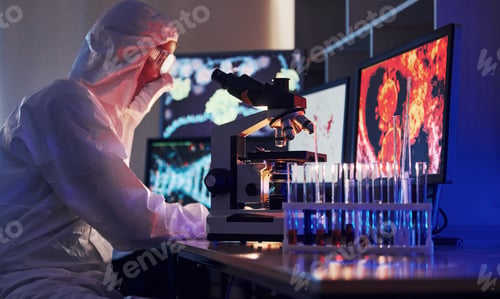 Preview: Scientist in white protective uniform works with coronavirus and blood tubes in laboratory