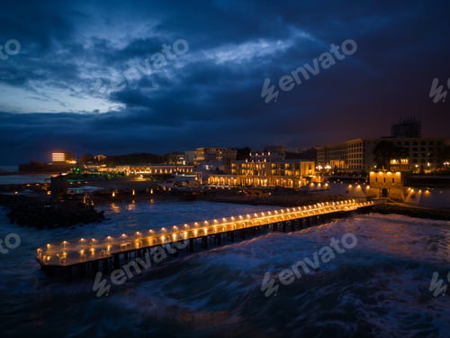 Preview: illuminated pier with dramatic sky over stormy dark sea at evening, Varna Bulgaria