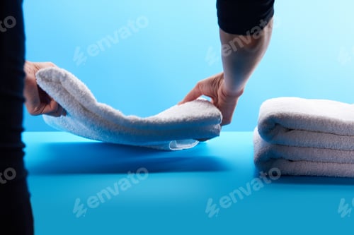 Visualização: foto recortada de pessoa empilhando toalhas brancas limpas em azul