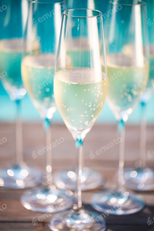 Preview: Champagne glasses on wooden background near pool