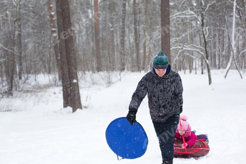Preview: Dad rides his daughter on a tube from a slide in winter in a snowfall