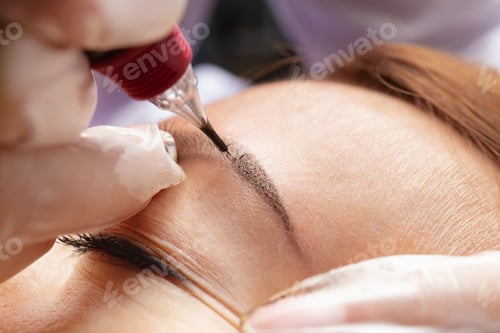 Preview: Beauty master performs permanent eyebrow makeup in a beauty salon, microblading, close-up