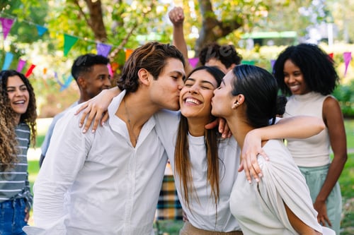 Preview: Friends kissing woman on cheeks at a park party