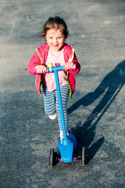 Preview: Little adorable girl having fun riding on scooter in the countryside