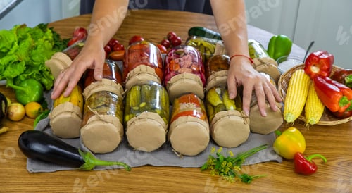 Preview: Woman canning vegetables in jars in the kitchen. Selective focus.