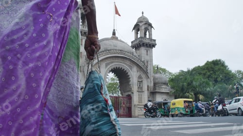 Preview: A woman in a colorful saree walking near the historic Khanderao Market gate in Vadodara, India