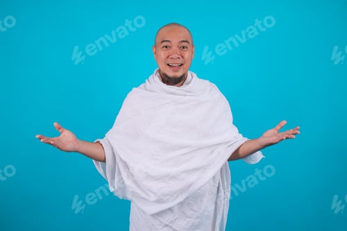 Preview: Portrait of Cheerful Muslim Pilgrim Wearing Ihram Cloth, Gesturing Welcome