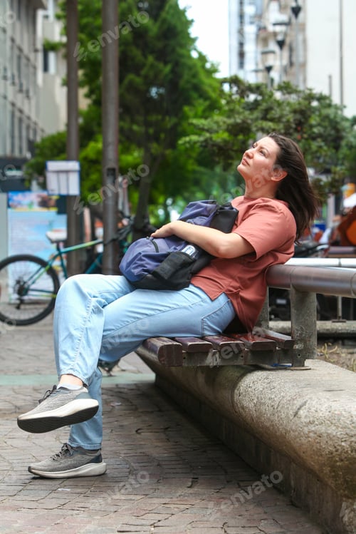 Preview: Daydreaming Woman Sitting on Bench on City Street
