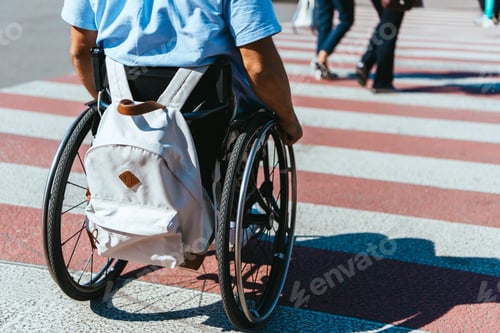 Preview: cropped image of man in wheelchair with bag riding on crosswalk