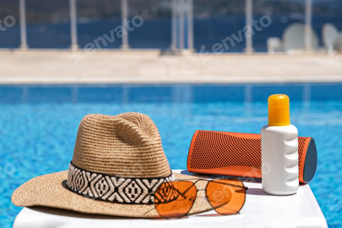 Preview: orange coloured beach accessories near swimming pool. Sun cream, sunglasses, speaker and hat