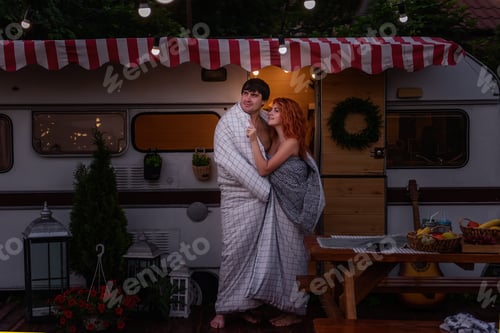 Preview: A young couple of happy lovers wrapped themselves in a white blanket by the trailer truck