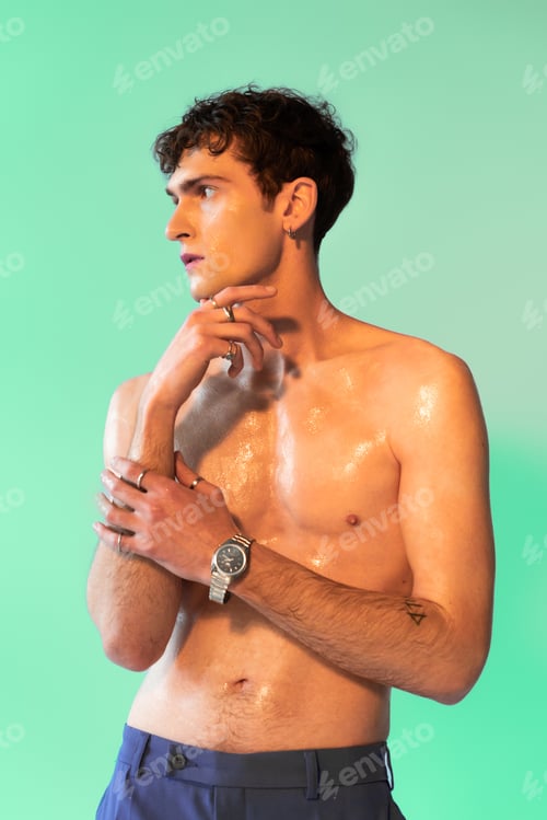 Preview: Shirtless man with fingerings and oil on body posing on green background