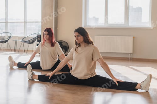 Preview: the two girls on a group fitness training class in the gym doing stretching workout