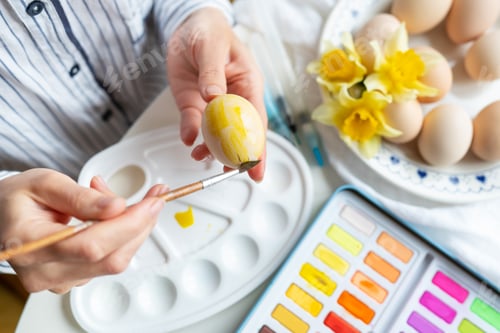 Preview: A brush in the process of painting Easter eggs with watercolors. The concept of preparing for Easter