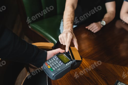 Preview: Cropped view of waiter holding payment terminal near man with credit card in bar