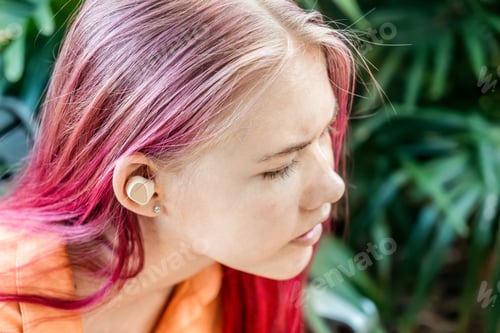 Preview: Teenage girl with ombré pink colored hair wearing wireless earbuds earphones