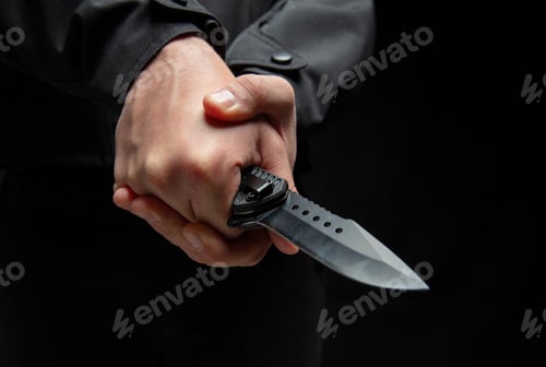 Preview: Criminal holding a knife with both hands closeup, armed attack concept.