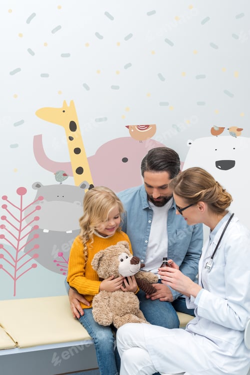 Preview: young doctor giving syrup to teddy bear of little girl