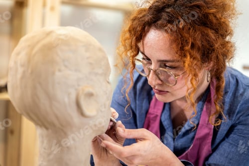 Preview: Female sculptor working in pottery studio workshop sculpting human head.