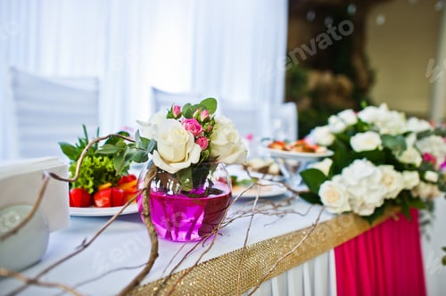 Preview: Flowers on vase with pink water at table of newlyweds.