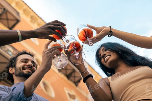 Preview: Low-angle view of friends toasting with rosé wine