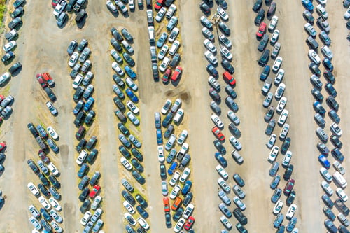 Preview: Large vehicle storage yard filled with abandoned cars and trucks organized in rows during daytime