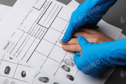 Preview: Investigator taking fingerprints of suspect at table, closeup. Criminal expertise