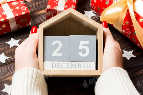 Preview: Top view of female hands holding a calendar on wooden background.