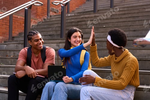 Preview: Diverse students high fiving celebrating success on university steps