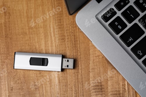Preview: Modern laptop and usb flash drive on wooden table, flat lay