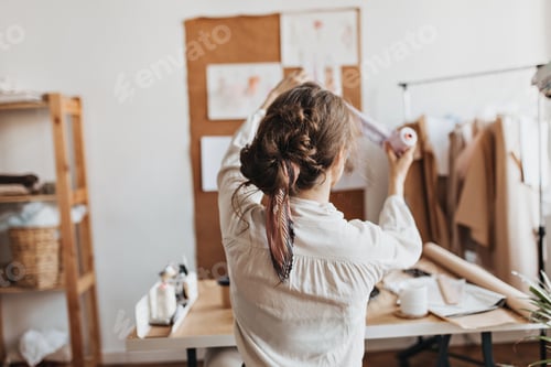 Preview: Stylish woman holds thread to create new clothes. Dark-haired lady with ponytaill works on new fash