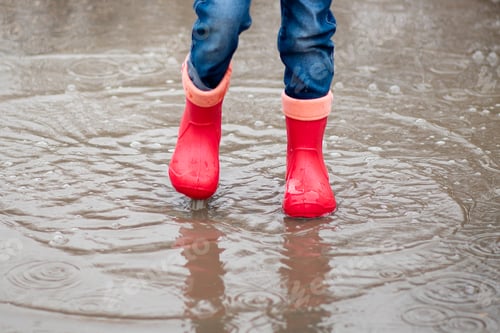 Preview: A cute little girl red boots jump in puddles and has a fun. Happy childhood. Early spring. Emotions.