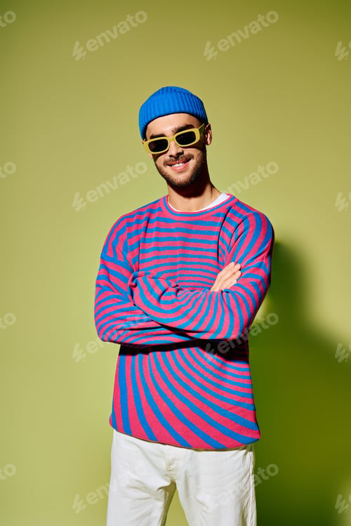 Preview: Young man displays vibrant fashion against a bright green studio backdrop