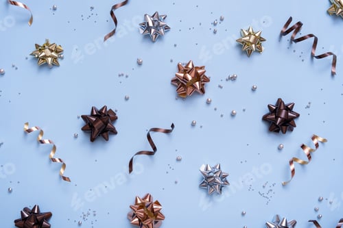 Preview: Bright festive background with bows and beads top view. New Year Christmas blue background flat lay