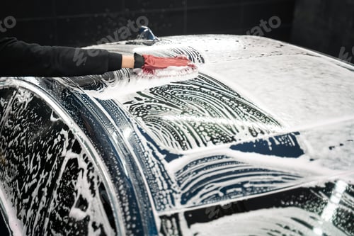 Preview: Professional car wash. Detailing worker washes the vehicle body with foam and rag