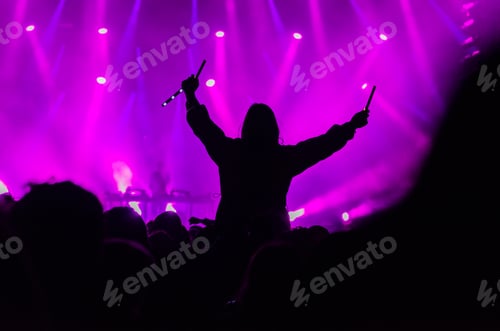 Preview: Silhouette of a girl cheering above the crowd at a music festival