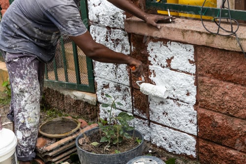 Preview: Painter worker adding undercoat foundation paint onto wall with roller at residential building in