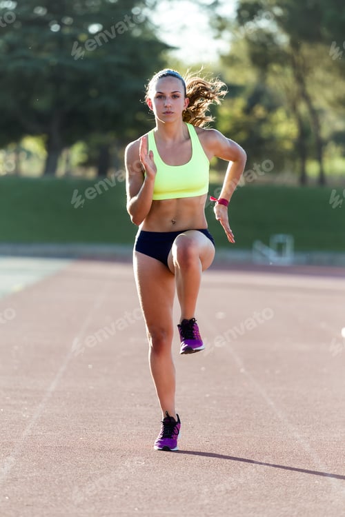Preview: Fit young woman running on track field.