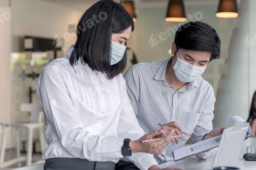 Preview: Asian businessman and businesswoman wearing wearing to protect against germs work together at the of