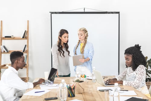 Preview: multicultural businesswomen using tablet while african american colleagues working on laptops in