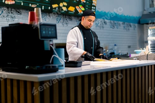 Preview: Sushi chef in the process of preparing a philadelphia roll with seared salmon cream cheese cucumber