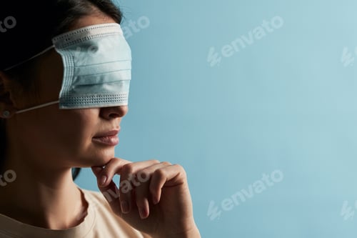 Preview: Serious young female posing in studio with antivirus mask