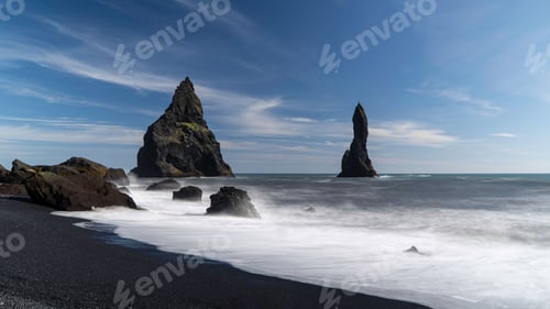 Preview: Scene of the Reynisfjara Black Sand Beach with high, heavy rocks under the blue sky in Iceland