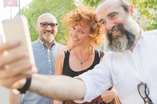 Preview: Mid adult woman and male friends taking smartphone selfie on city street