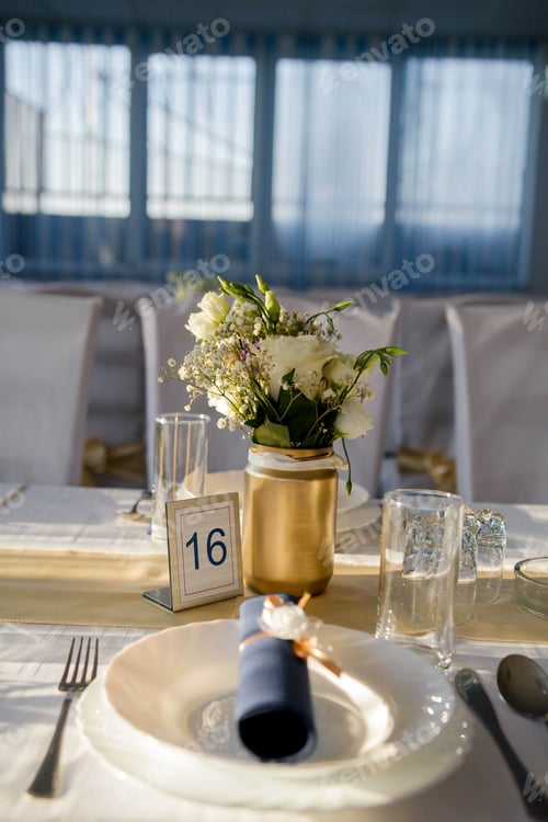 Preview: Vertical shot of an elegant table set-up in a wedding reception with the number 16 on top